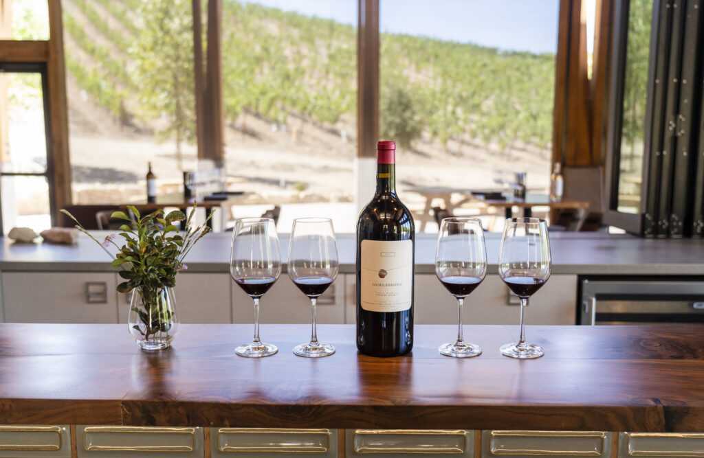 bottle and glasses on bar with vineyard in background