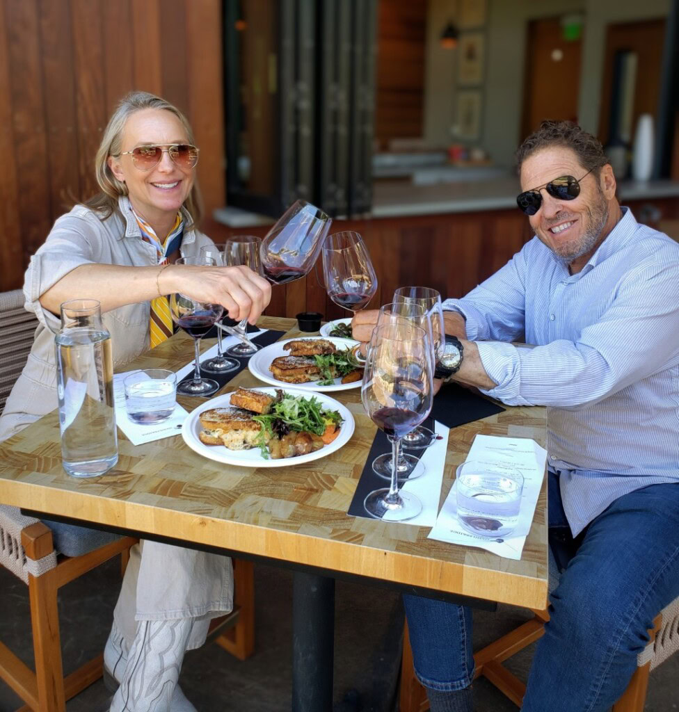 A man and women at Sixmilebridge enjoying the Estate Flight & Grilled Cheese experience. Pictures shows the two seated at a table with various glasses of wine and their grilled cheese food pairing.