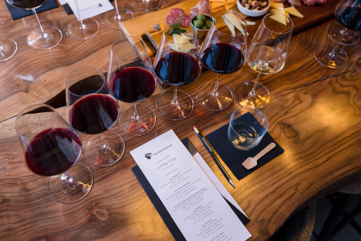 Table setting of six wine glasses, 5 reds and 1 white, with a tasting menu 